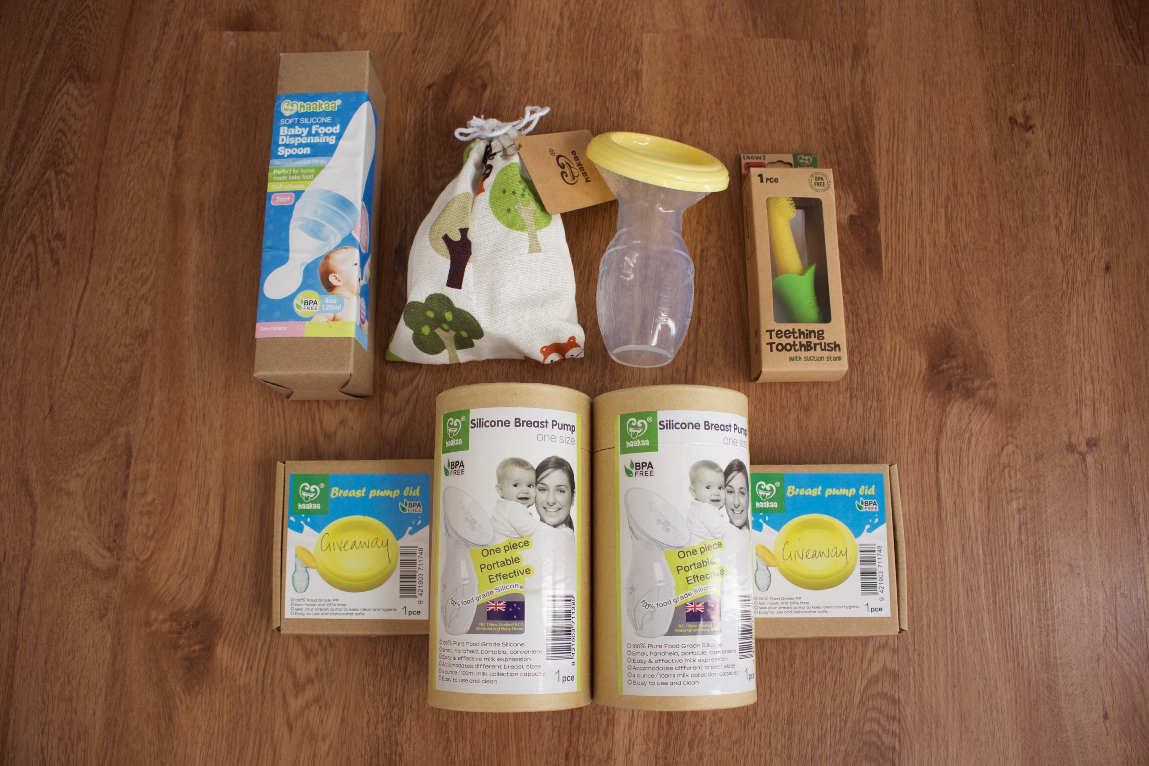 Haakaa Breast Pump review - a selection of products from Haakaa including the Haakaa breast pump, a teething toothbrush, a baby food dispensing spoon and the Haakaa breastpump lid