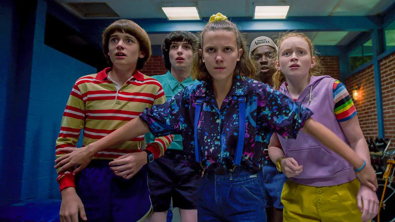 Eleven in season 3 of Stranger Things holds her arms out to protect her friends
