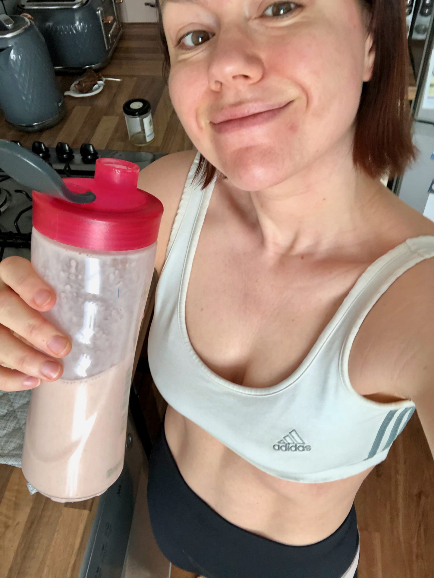 A woman in a sports bra drinks a protein smoothie