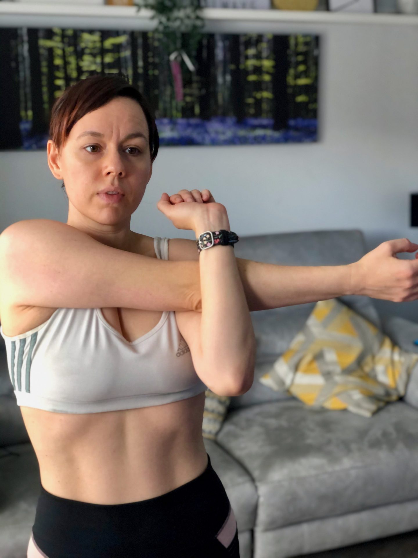 A woman wearing a sports bra stretches her arms