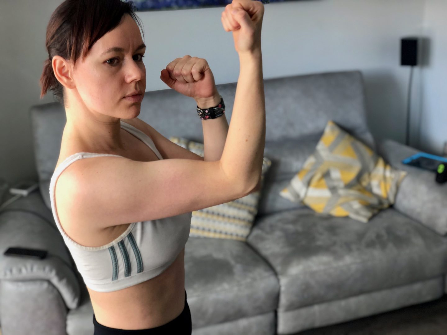 A woman flexes her biceps in a sports bra