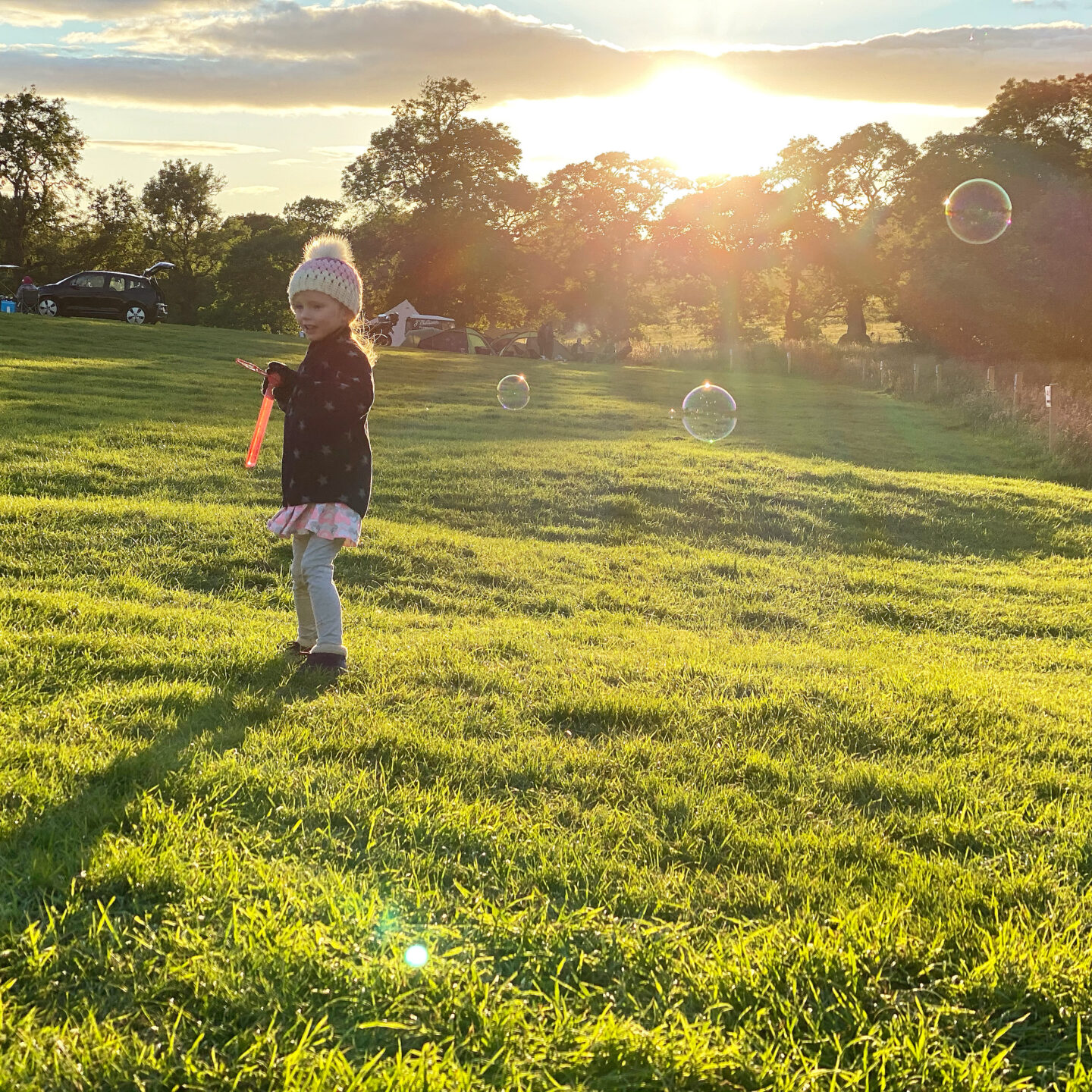 Little girl playing with bubbles at sunset