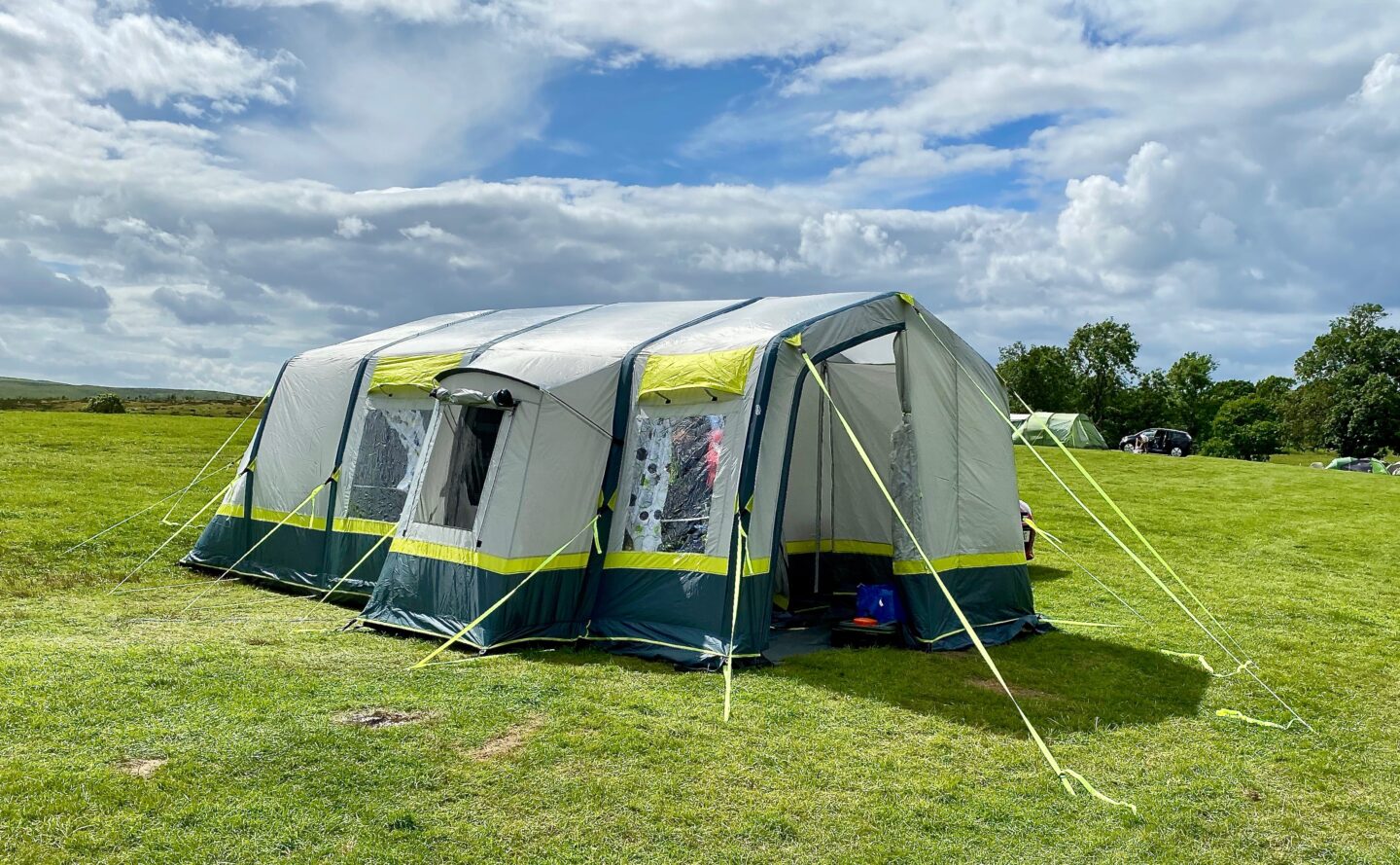 The OLPRO Home 5 berth family tent which is large, light grey, blue and neon green accents in a field.