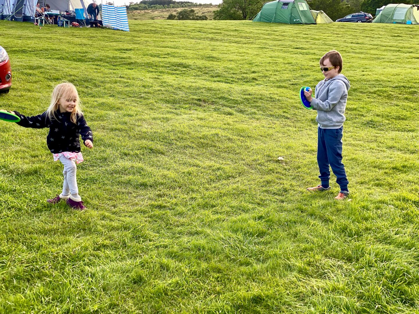 two children playing catch on a campsite 