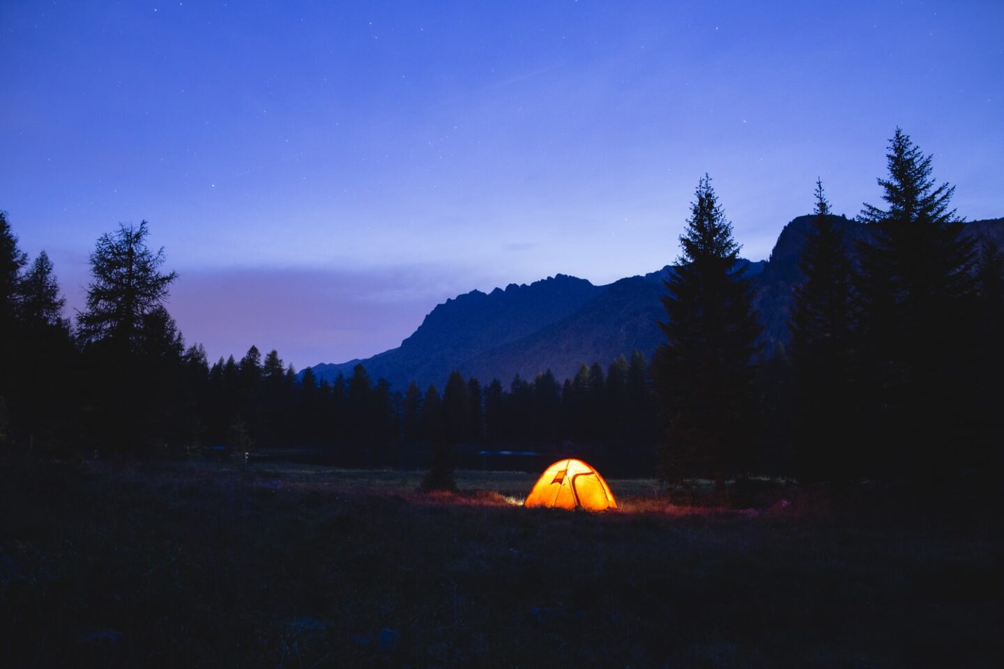 Tent glowing against the mountains during free camping at night.