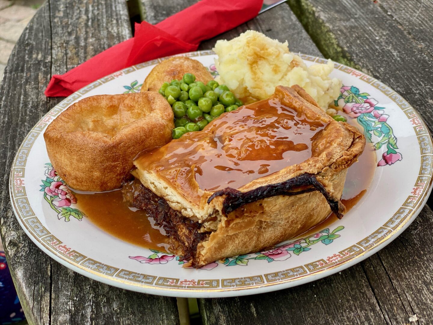 Pie, mash, peas, yorkshire pudding and gravy on a plate