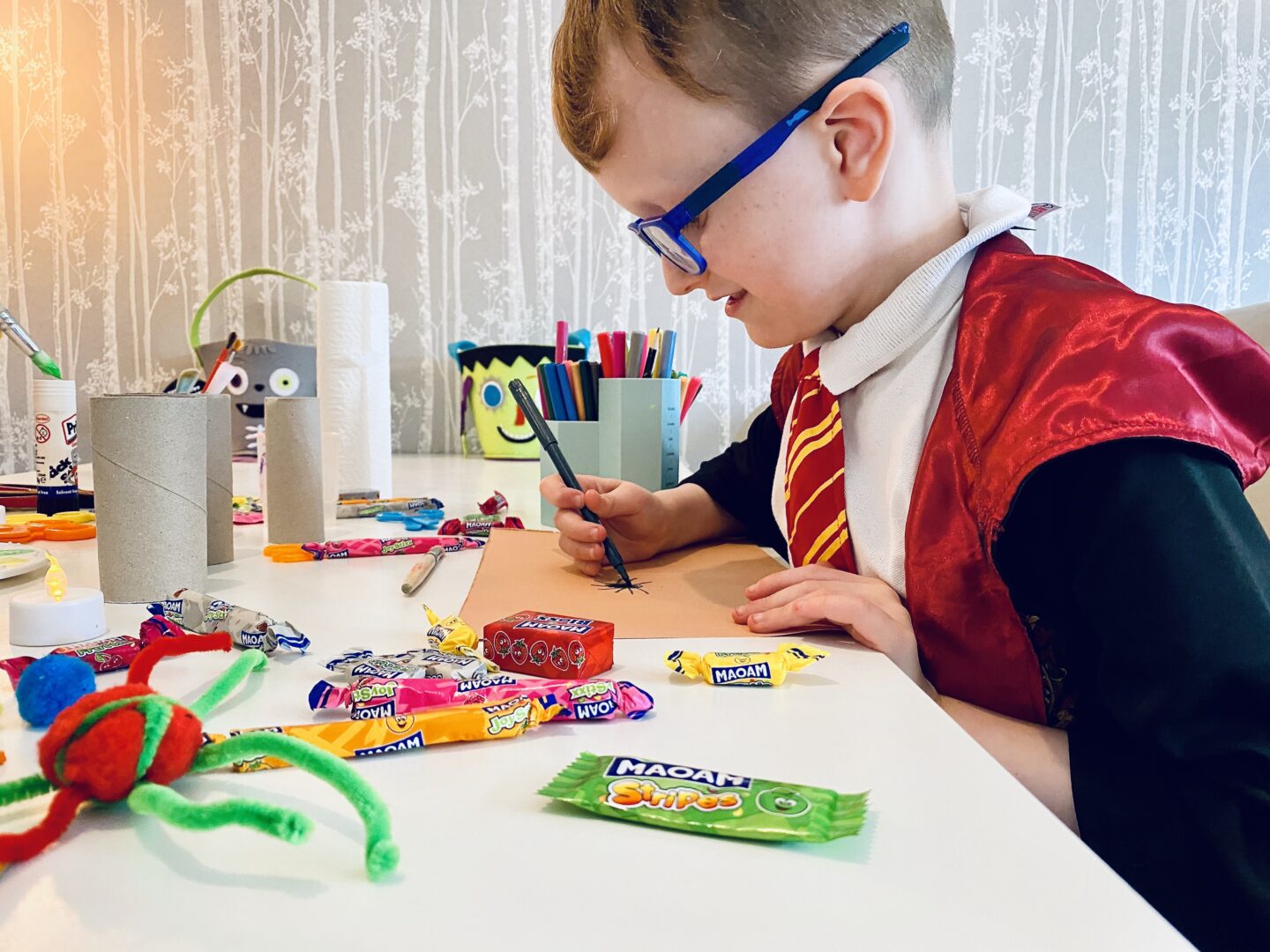 A boy dressed as Harry Potter doing Halloween crafts