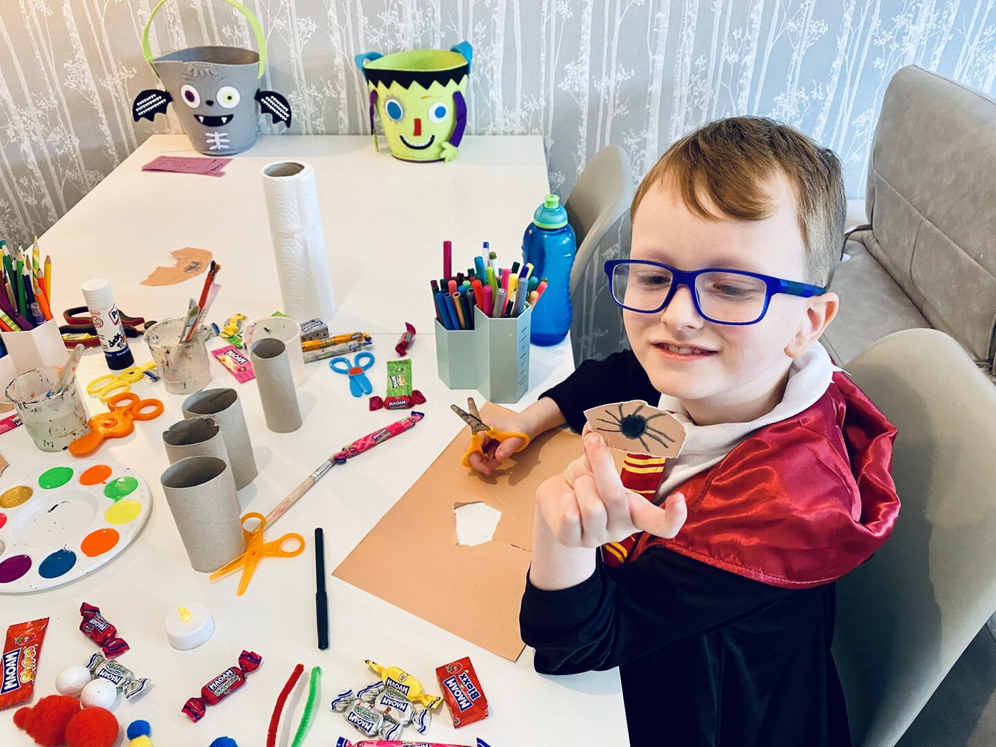 A boy wearing glasses showing off a spider that he has drawn