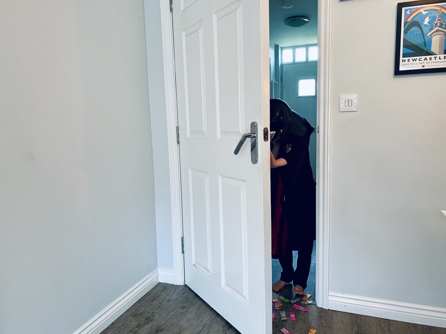 A boy opening a door and sweets falling down. 
