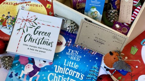 A box full of Christmas items like hot chocolate, books and an elf