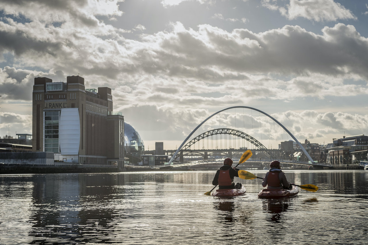 a couple kayaking near bridges over a river