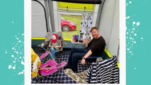 A father and son sat on camping chairsinside of a tent