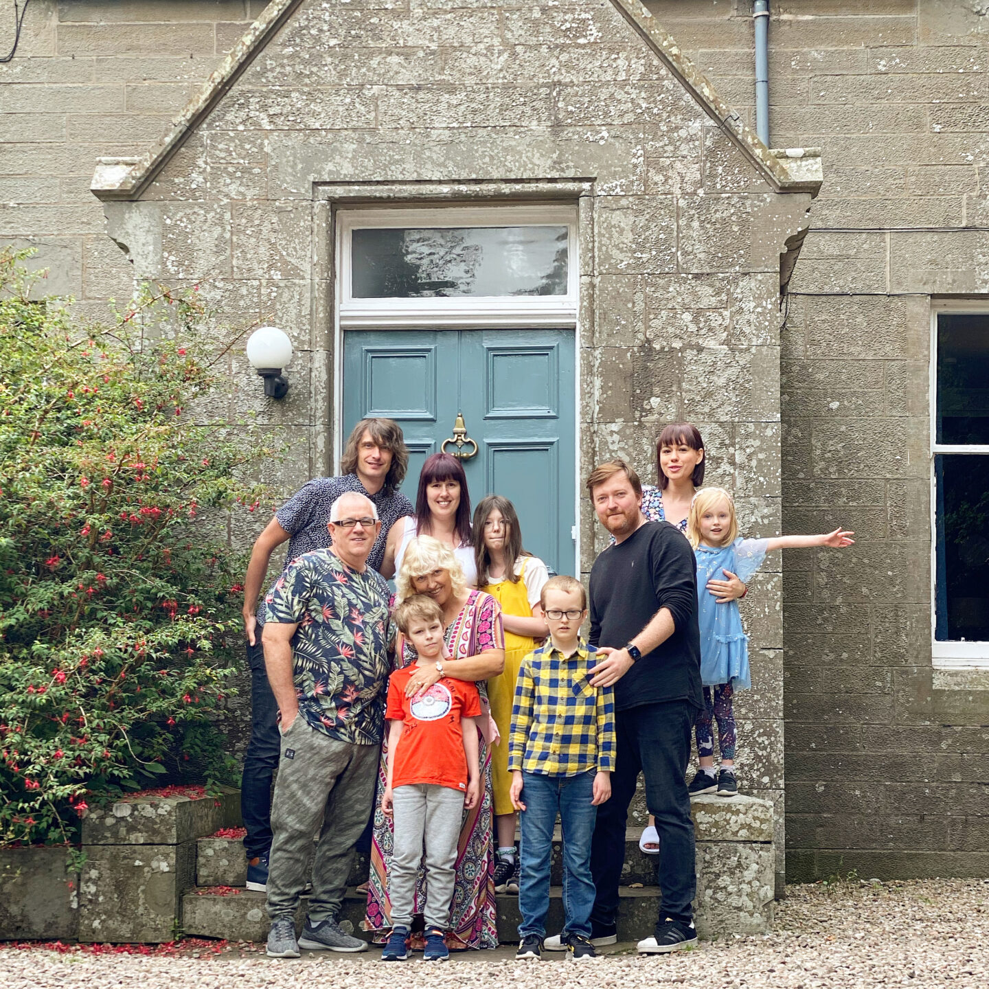 A large family photograph outside the blue front door of Slade House, Angus, Scotland