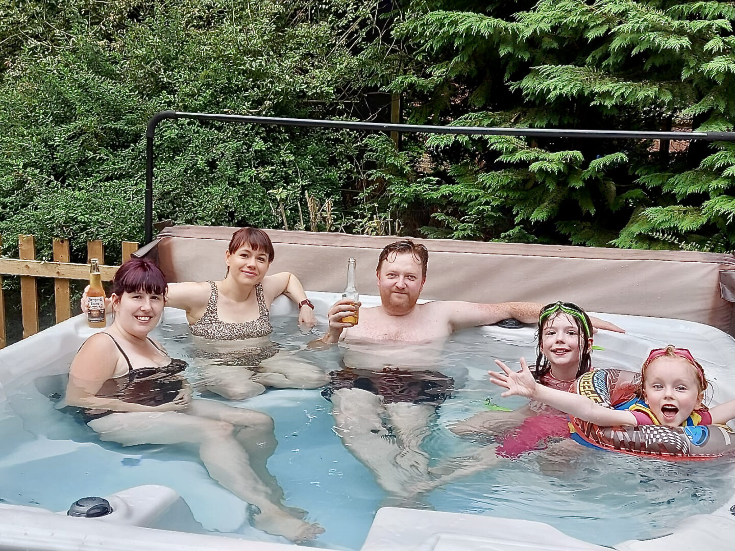 2 women, a man and 2 girls in a hot tub smiling and having fun. 