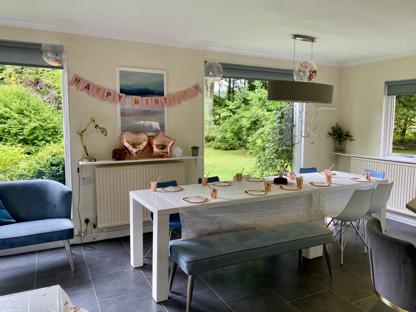 A large kitchen with a white table decorate for a birthday with rose gold decorations