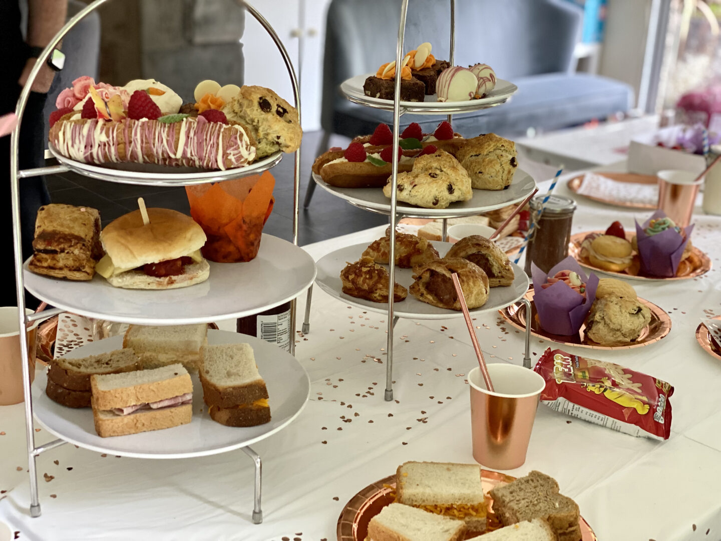 An afternoon tea set out on a dining table on cake stands 