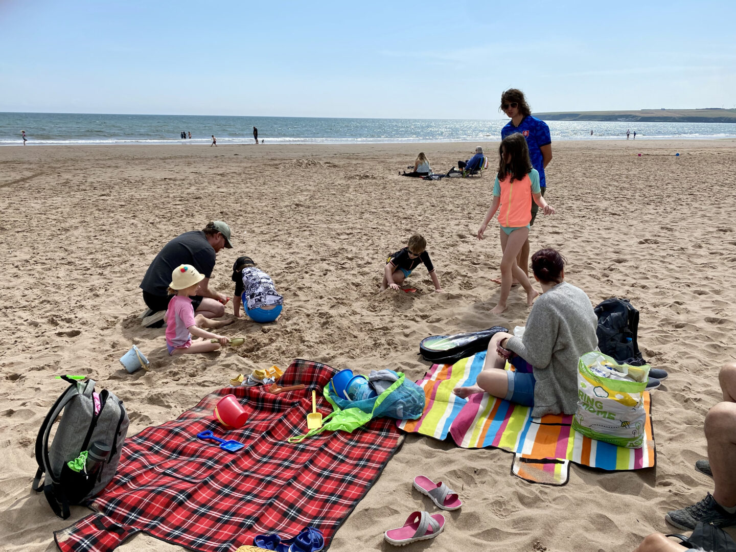 A family play on the beach next to a tartan picnic blanket at Lunan Bay, Angus, Scotland