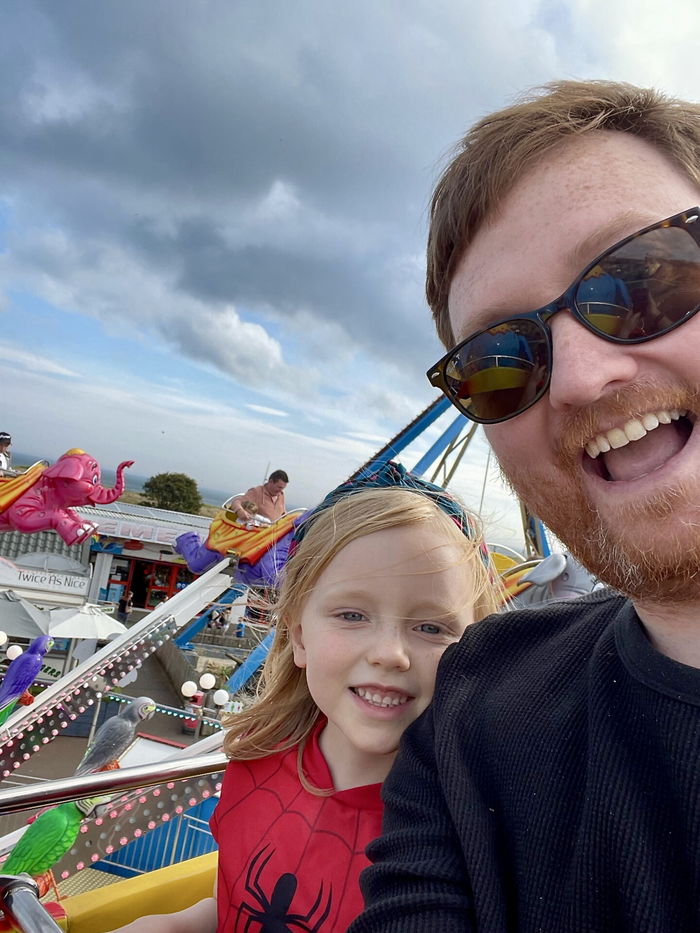 A father and daughter smiling on a fairground ride 