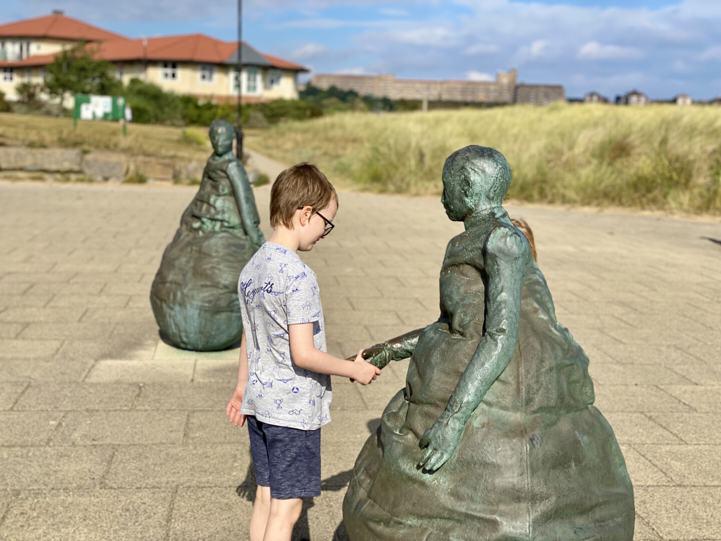 A boy 'shakes hands' with a statue