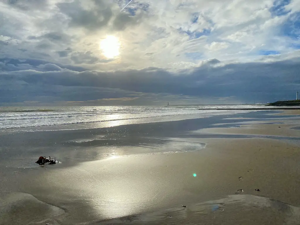 The sun shines behind the clouds on an empty beach