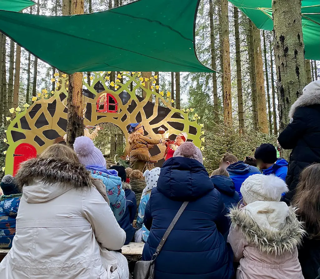 Performers perform on an ornate stage in the woods