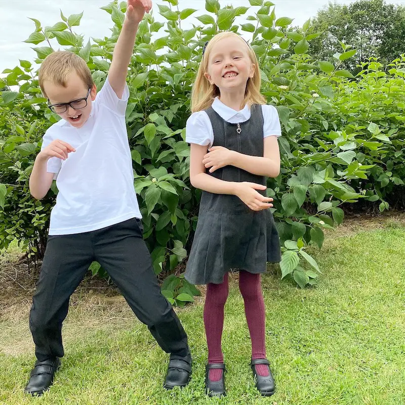 2 children wearing school uniform looking happy