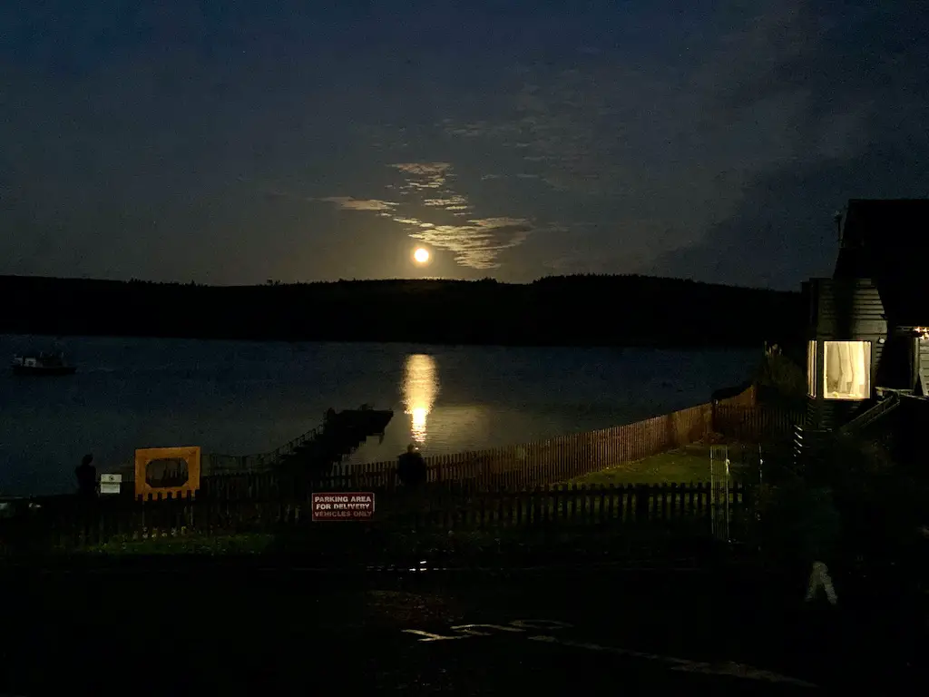 A full moon shines a bright beam of water across a lake. 