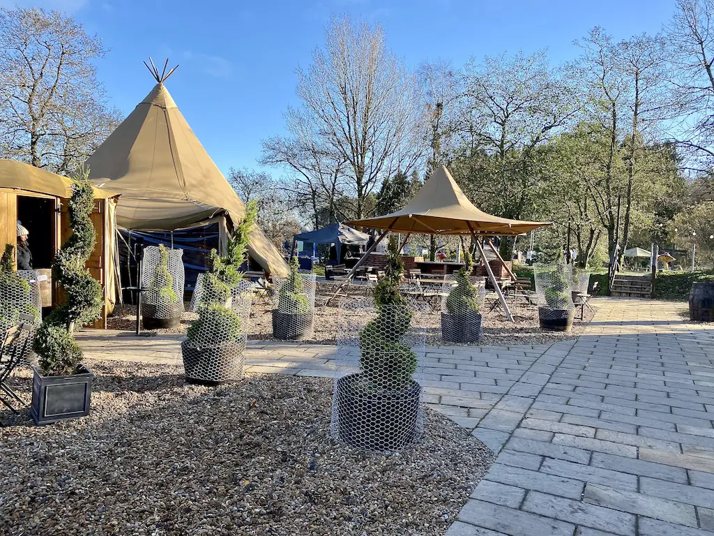 Some teepees set up and little green swirling trees around them. 