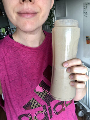 Woman in a pink adidad sports top holds a chocolate banana smoothie