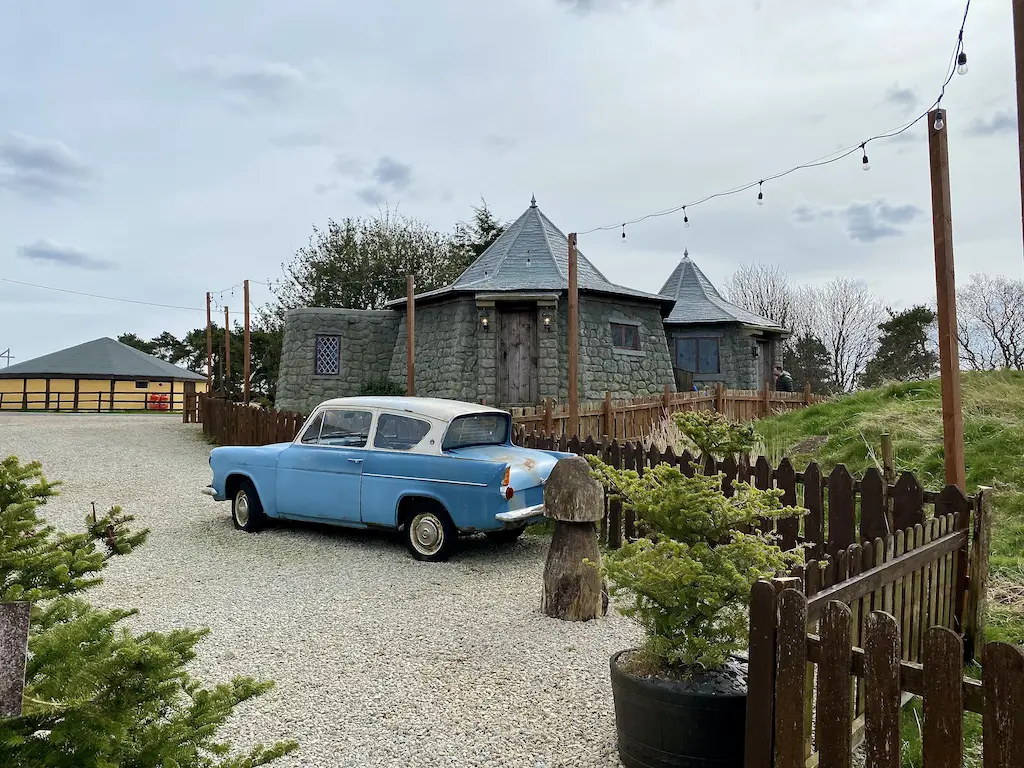 Blue 1960 Ford Anglia 105E in front of a replica of Hagrid's hut from Harry Potter