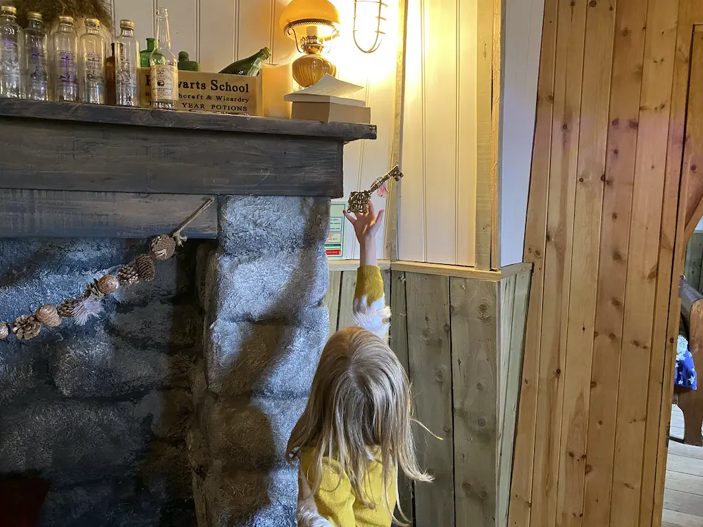 Little girl reaches up to touch a flying key hanging from the ceiling