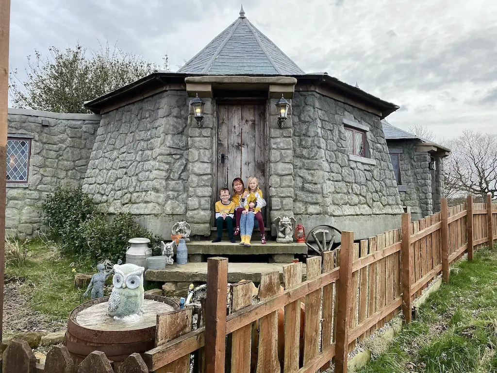 A family sat on the steps of a replica of Hagrid's Hut from Harry Potter