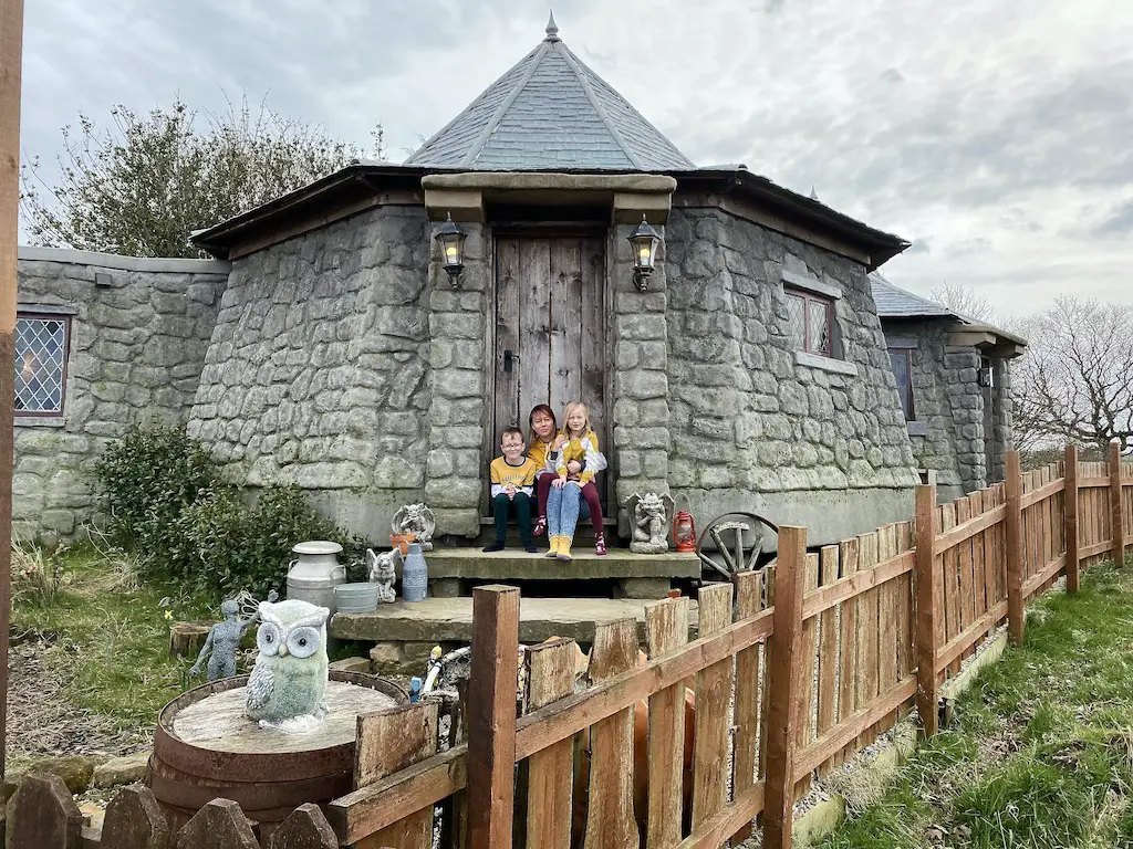 A family sat on the steps of a replica of Hagrid's Hut from Harry Potter 