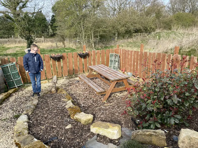 Boy stands in the garden with a picnic table