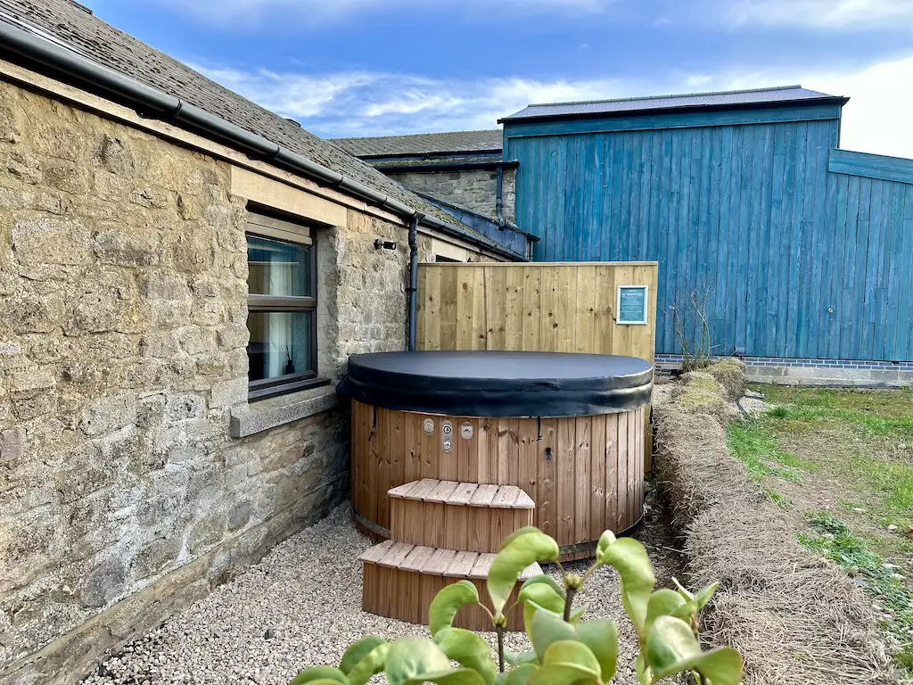 Wooden hot tub with steps leading to it next to a stone Courtyard Suite room at Runa Farm Barnard Castle 