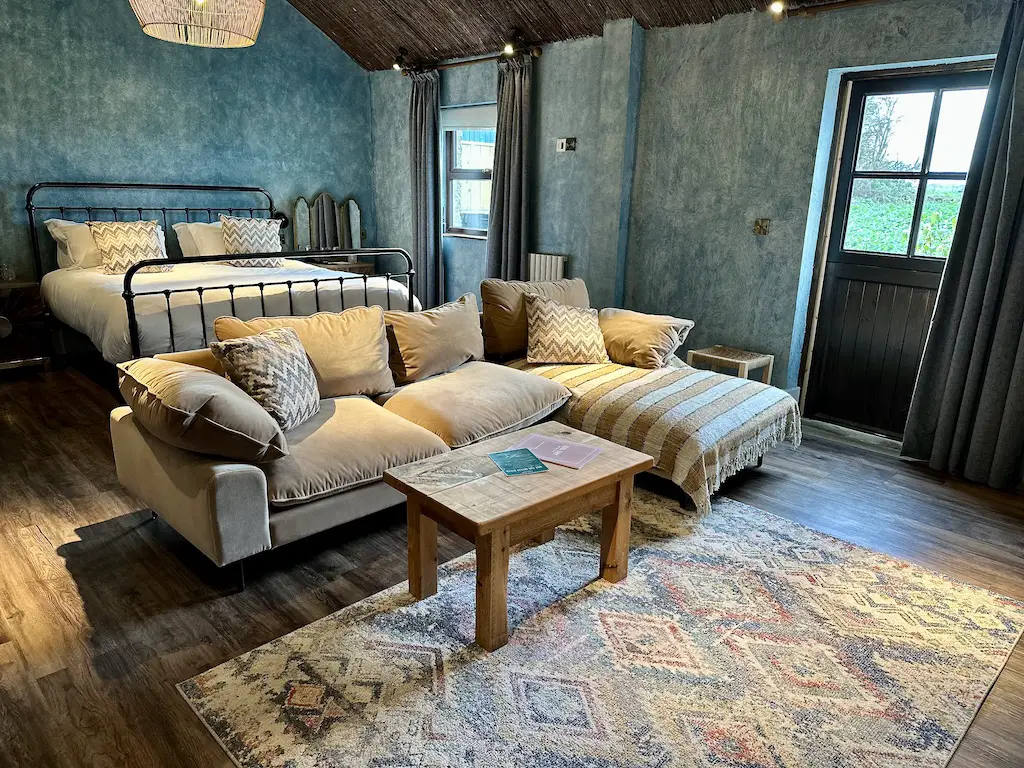 Courtyard suite room at Runa Farm showing a cream corner sofa in front of a double bed