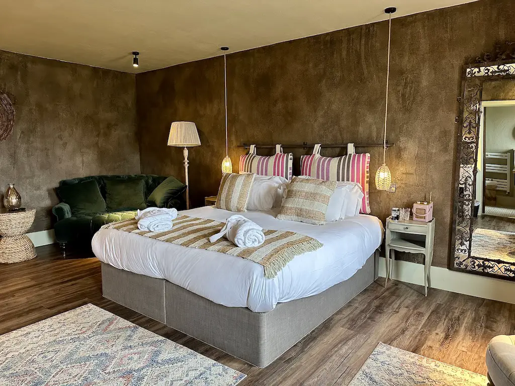 A bedroom featuring a double bed, a velvet chair and a large mirror at Runa Farm's Farmhouse