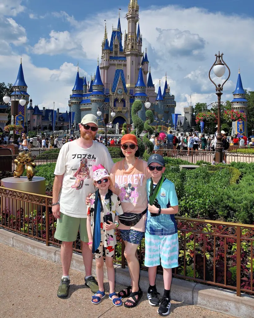 A family of 4 stand in front of the castle at Magic Kingdom 