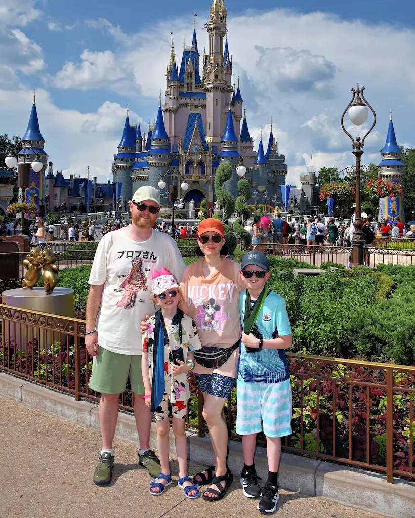 A family of 4 stand in front of the castle at Magic Kingdom