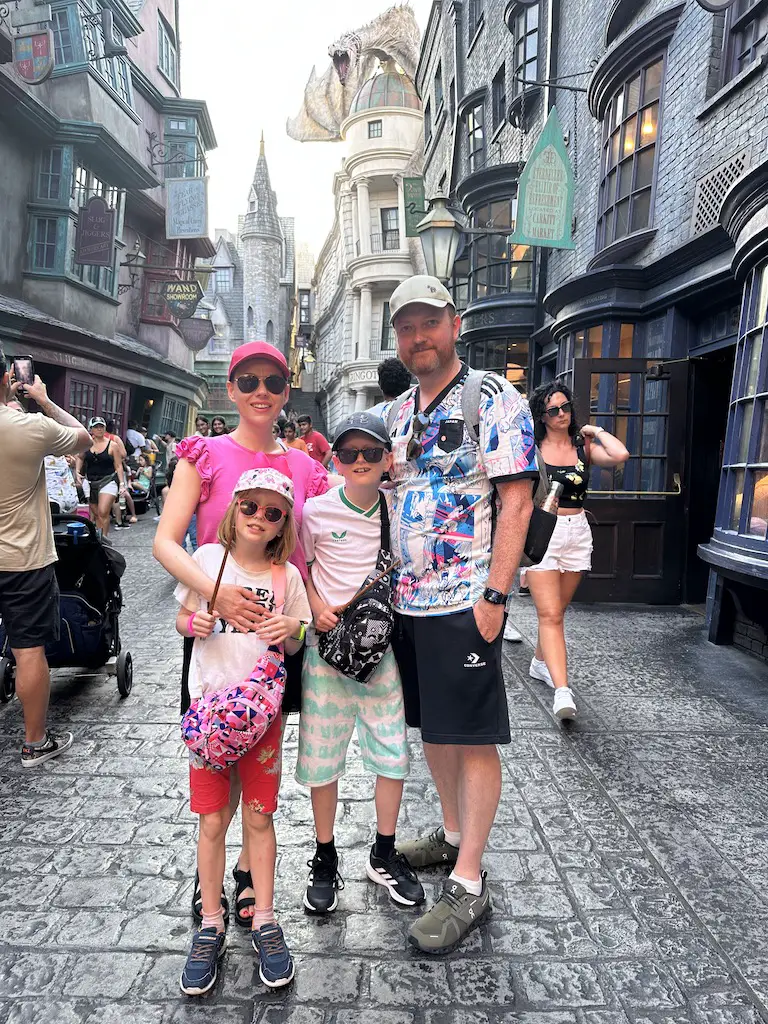 A family of 4 stands in front of the Gringotts Bank in Diagon Alley at Universal
