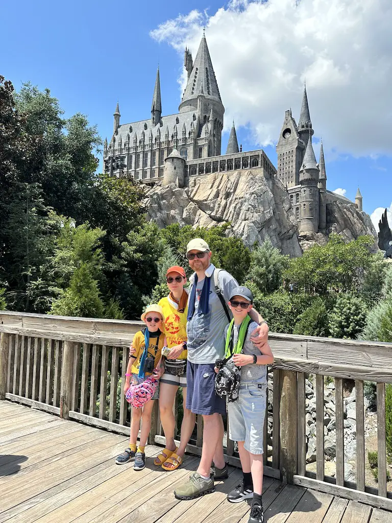 A family of 4 stand on a bridge in front of Hogwarts Castle at Universal - Orlando 14 day itinerary 