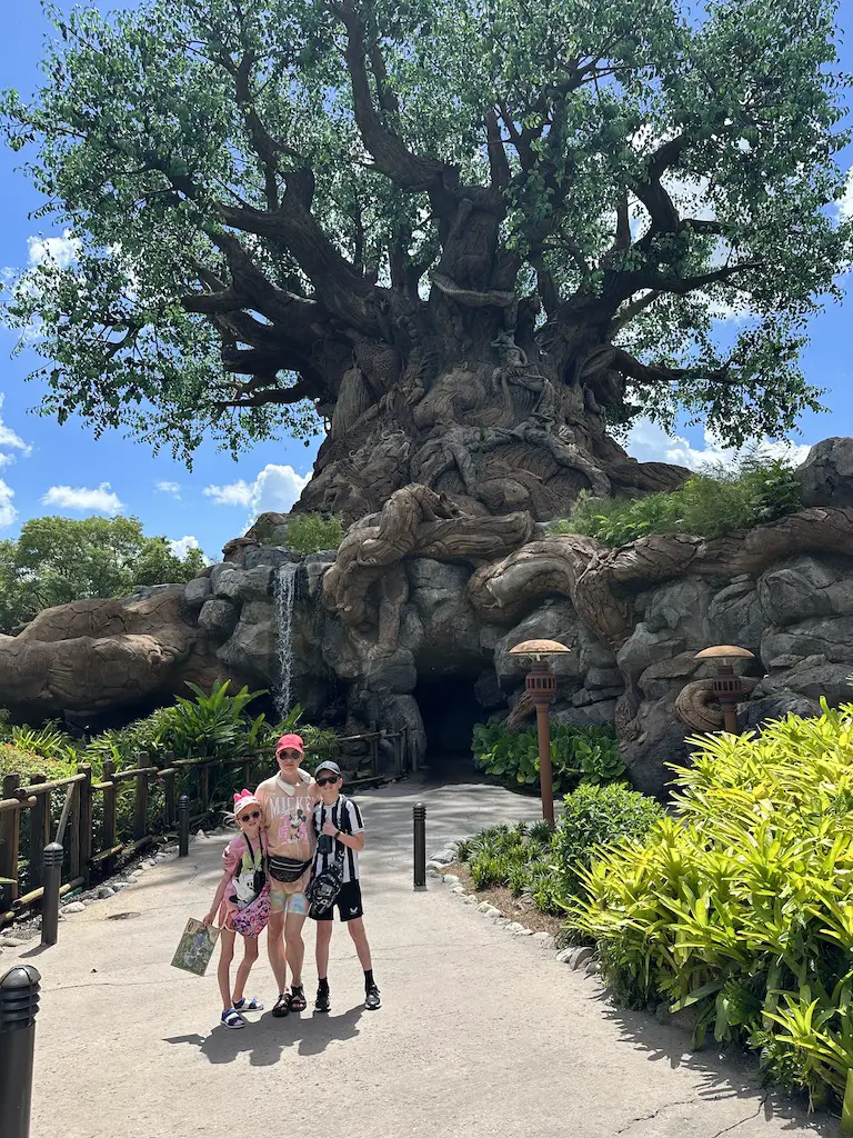 A mother, son and daughter stand in front of the Tree of Life at Animal Kingdom 