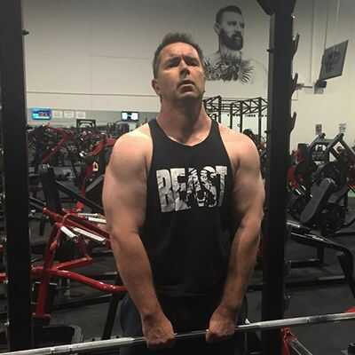 Photo of muscular man lifting a bar. What factors should be considered when designing a personal fitness program?