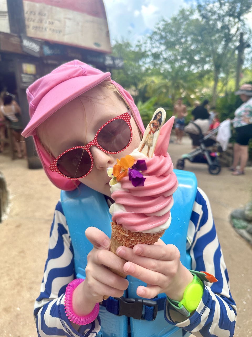 Girl eating pink Moana dole whip ice cream at Typhoon Lagoon waterpark at Disney World - 14 days Orlando itinerary.