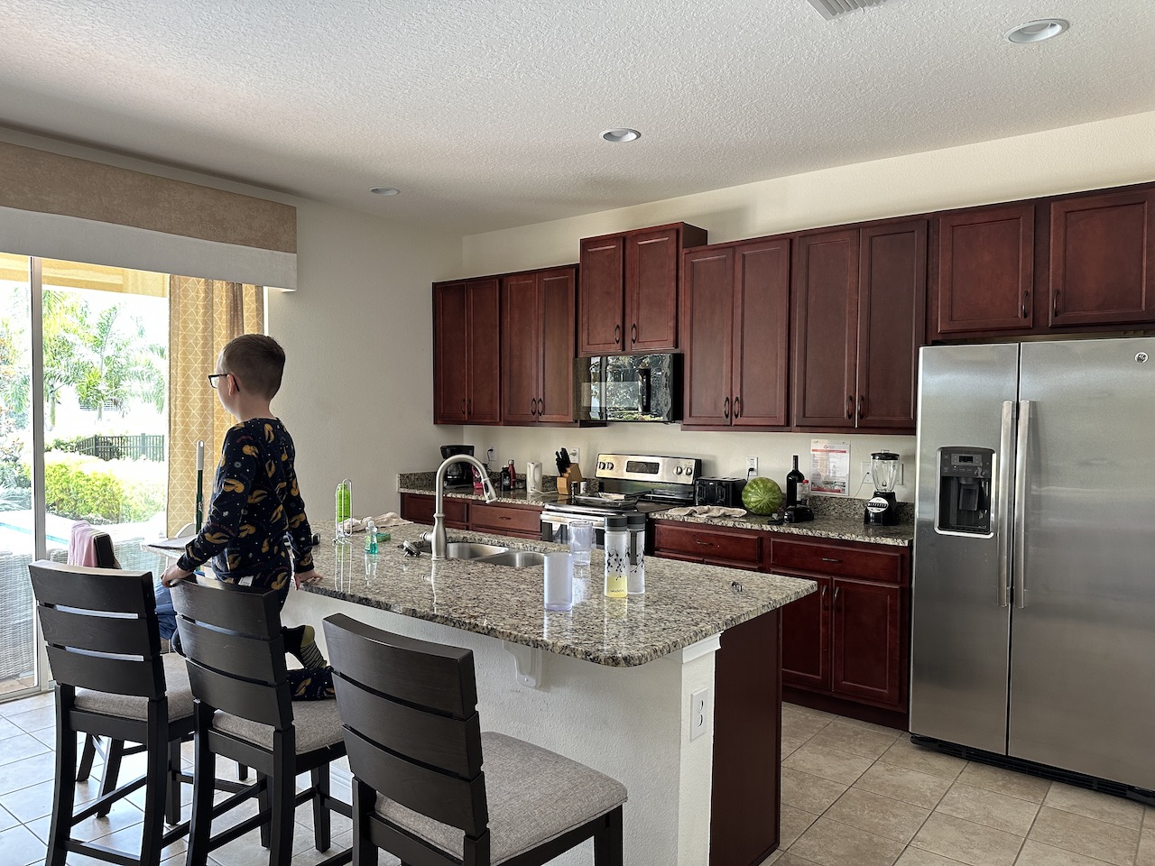 encore orlando 5 bedroom villa kitchen area with dark wooden cabinets, american fridge freezer and breakfast bar