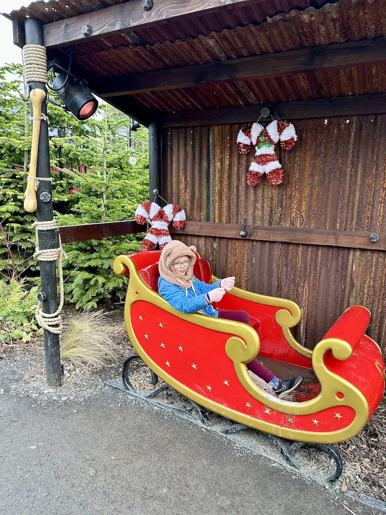 Santa's sleigh at Lilidorei - a red sleigh with gold trim with a little girl sat in it pretending to ride it