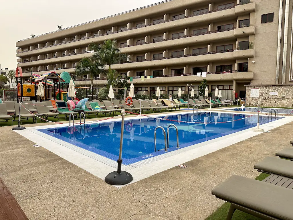 A small pool next to a children's play area. 